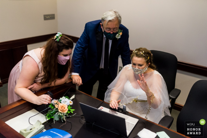 Texas wedding photography from the 2nd District Court of Appeals, Fort Worth showing A bride waving to her friends and extended family members on zoom after her civil ceremony Texas wedding photography from the 2nd District Court of Appeals, Fort Worth showing A bride waving to her friends and extended family members on zoom after her civil ceremony