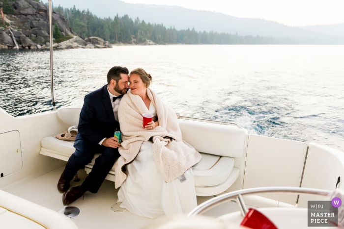 South Lake Tahoe, CA foto di matrimonio che mostra una sposa e uno sposo che condividono un momento di quiete insieme sulla loro barca charter privata, su cui sono fuggiti