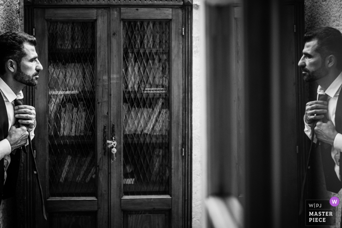 France home wedding photography of the groom working in a mirror to tie it up