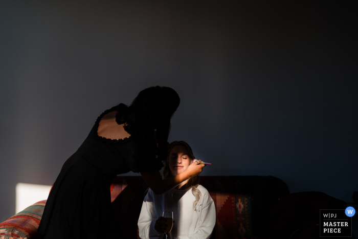 Pennsylvania Hotel wedding photography showing the Bride getting her makeup done by one of her friends after her first attempt at doing it herself was unsuccessful