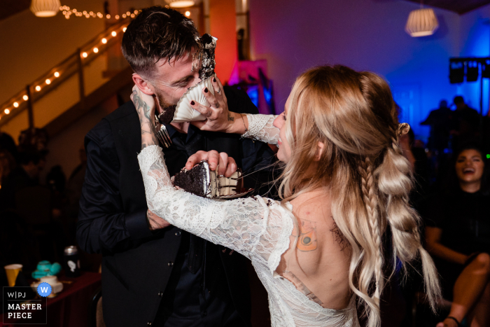 Foto de casamento da recepção na Pensilvânia mostrando a noiva decidiu que o marido merecia uma fatia de bolo na cara