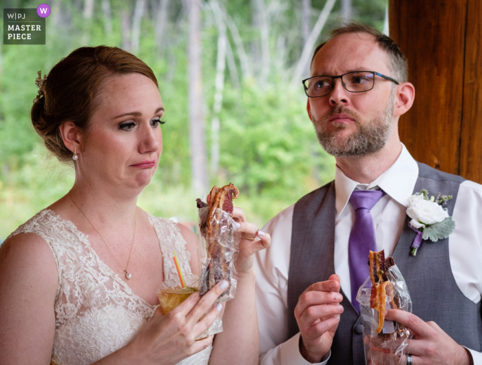 West Glacier, Montana, fotografia di matrimonio che mostra la sposa e lo sposo assaggiare i diversi antipasti di pancetta preferiti. A causa del COVID-19 tutti gli antipasti dovevano essere confezionati singolarmente