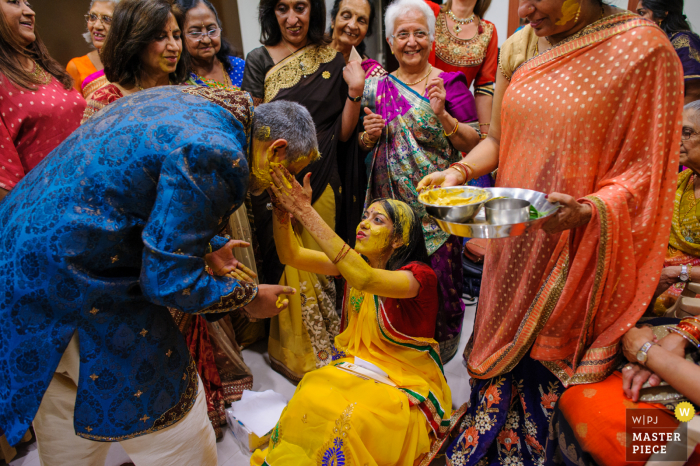 Foto de casamento da Comunidade Hindu de Portugal, Lisboa, Portugal mostrando o O padrinho da noiva também foi abençoado pela noiva na cerimônia Pithi, uma cerimônia de bênção para a noiva, sob o olhar de todos os familiares mais próximos da noiva