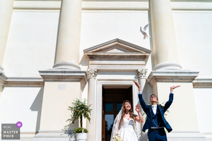 Pordenone, Italië huwelijksfotografie met de vlucht van de duif buiten de kerk