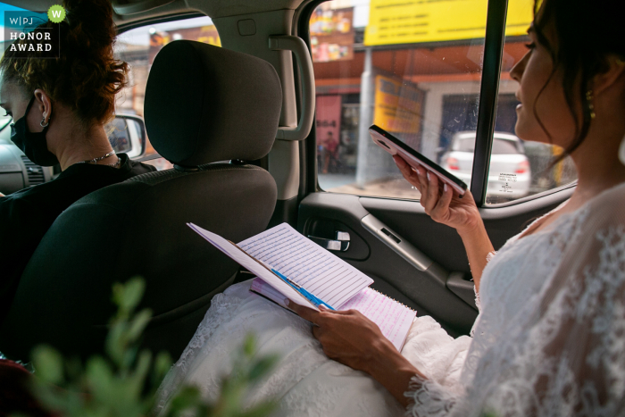 Novia de Goiás sentada en el asiento trasero de un coche mientras viajan por la ciudad el día de la boda