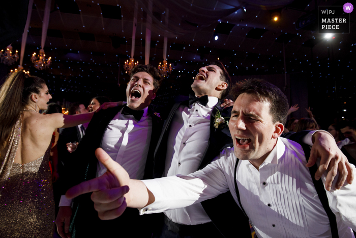 Fotografía de la boda de Seawell Ballroom que muestra al novio bailando con sus padrinos de boda durante la recepción de su boda en Seawell Ballroom en Denver, CO