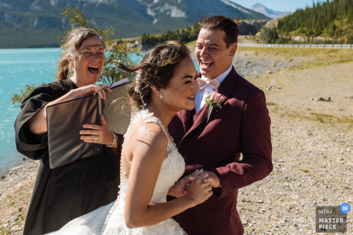 Lago Minnewanka, Parque Nacional Banff, AB, Canadá Fotografía de boda que muestra que la novia no podía poner un anillo en el dedo del novio