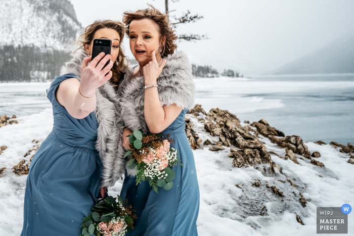 Lake Minnewanka, Banff National Park, AB, Canada huwelijksfotografie van bruidsmeisjes die een selfie-foto maken bij zeer koud weer