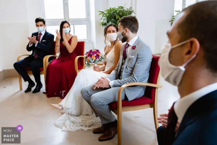 Het huwelijksbeeld van Parijs van de bruid en bruidegom die tijdens covid onder hun masker geloften uitwisselen