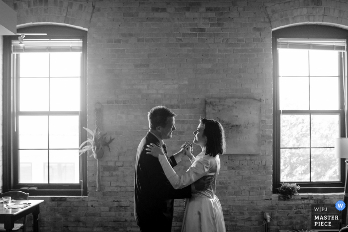 Fotografía de la boda del apartamento de la pareja en Madison, WI que muestra la danza del padre e hija en la sala de estar de la pareja en su boda reprogramada.