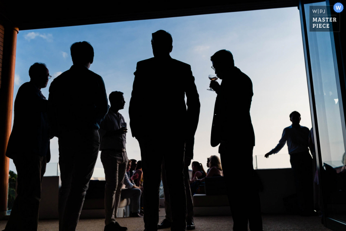 A top wedding photographer in London captured this picture of Guest having drinks silhouetted against the blue sky