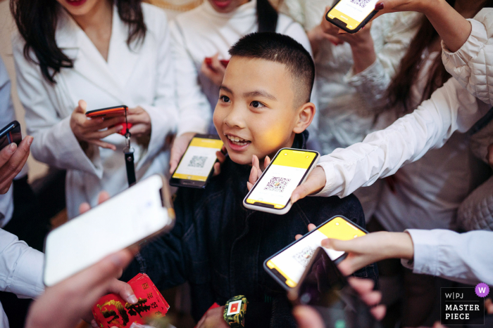 Um importante fotógrafo de casamento em Guangxi tirou esta foto do rosto de um menino cercado por telefones com códigos QR