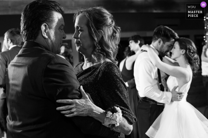 Um fotógrafo de casamento renomado em Allenspark, CO, no Wild Basin Lodge, tirou esta foto dos pais dos noivos compartilhando uma dança romântica em sua recepção de casamento