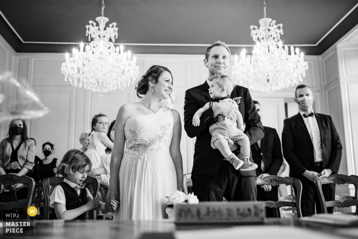 Um fotógrafo de casamento renomado em Rennes, Bretanha, tirou esta foto do noivo segurando uma criança pequena no balcão de casamento civil durante a cerimônia