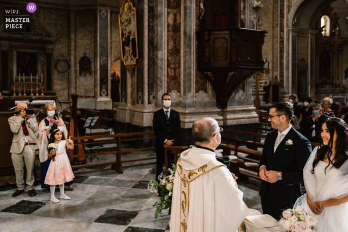 A wedding photographer in Puglia created this image of the flower girl inside the church gesturing to the bride and groom A wedding photographer in Puglia created this image of the flower girl inside the church gesturing to the bride and groom