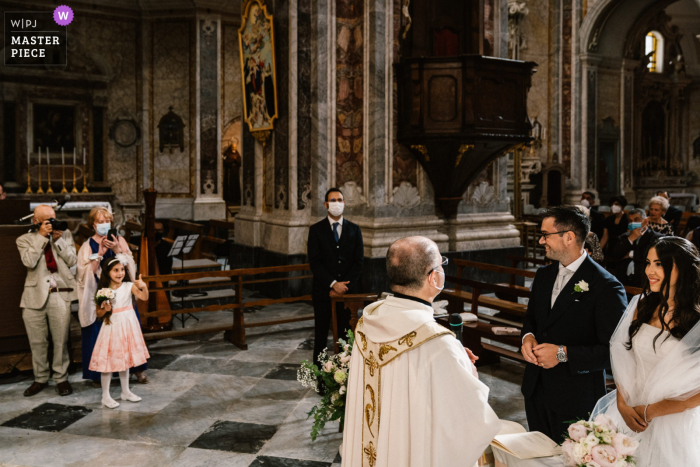 Ein Hochzeitsfotograf in Apulien hat dieses Bild des Blumenmädchens in der Kirche erstellt, das auf Braut und Bräutigam deutet