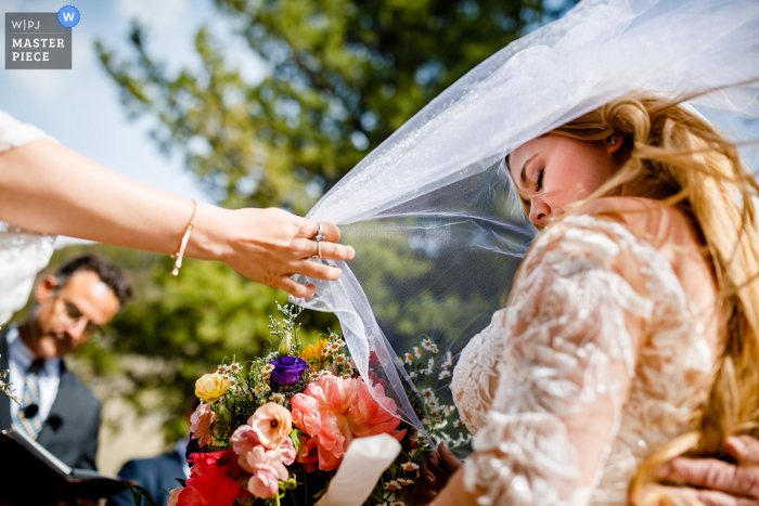 Czołowy fotograf ślubny w hrabstwie Summit w stanie Kolorado uchwycił to zdjęcie powiewającego welonu podczas modlitwy podczas ceremonii plenerowej