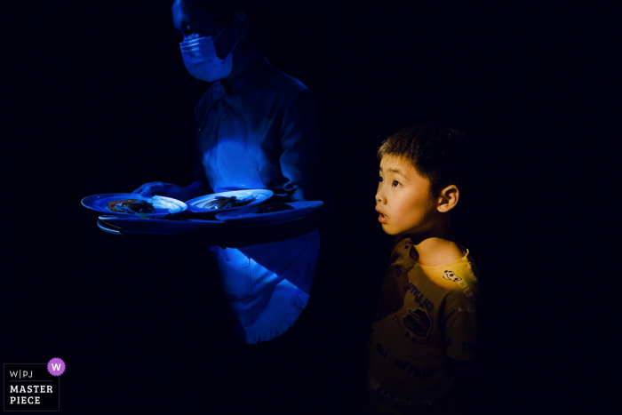 A top wedding photographer in Fujian captured this picture of a Waiter and child serving dishes at the wedding ceremony