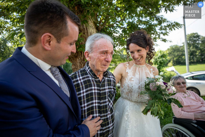 A wedding photographer in Occitanie created this image of Her handicapped grandpa is discovering Bride and groom after ceremony with emotion