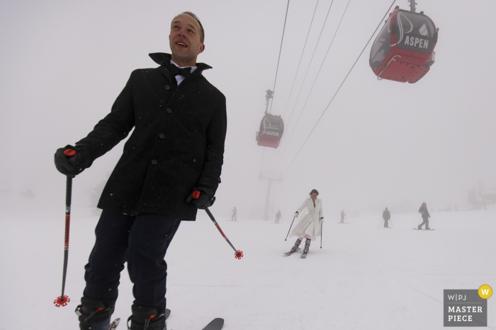 Un fotografo di matrimoni del Colorado ad Aspen Mountain ha creato questa immagine degli sposini che sciano giù per la montagna innevata dopo la loro cerimonia nuziale invernale winter