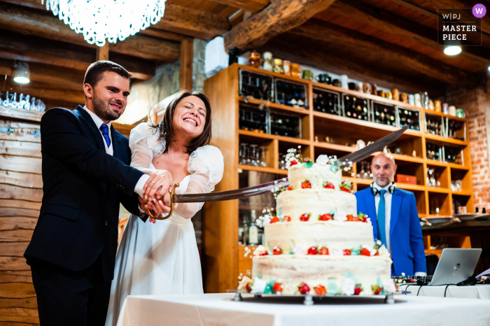 Ein Top-Hochzeitsfotograf aus Bulgarien im Chateau Copsa hat dieses Bild vom Kuchenschneiden mit einem großen Schwert aufgenommen