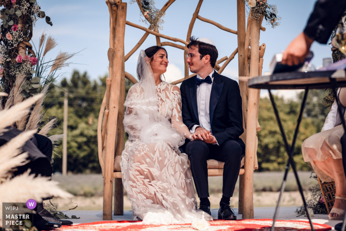 Ein Top-Hochzeitsfotograf von Solerieux in Les Domaines de Patras hat dieses Bild des Komplizen-Looks zwischen Braut und Bräutigam während der Zeremonie im Freien festgehalten