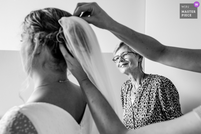 A melhor fotografia de reportagem de casamento da Holanda em Maassluis mostrando uma foto de uma mãe orgulhosa olhando quando o véu está preso à noiva