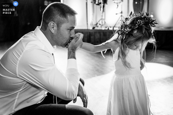 Ein Top-Hochzeitsfotograf in Pennsylvania hat dieses Bild aufgenommen, das den Vater des Blumenmädchens zeigt, der verschiedene Bestechungstechniken versucht, um seine Tochter dazu zu bringen, ihr Abendessen zu essen. Er begann mit einem Ringknall