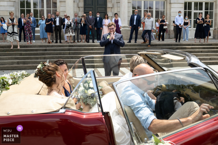 Um fotógrafo de casamento renomado em Limoges tirou esta foto da chegada da noiva na parte de trás de um automóvel vintage conversível