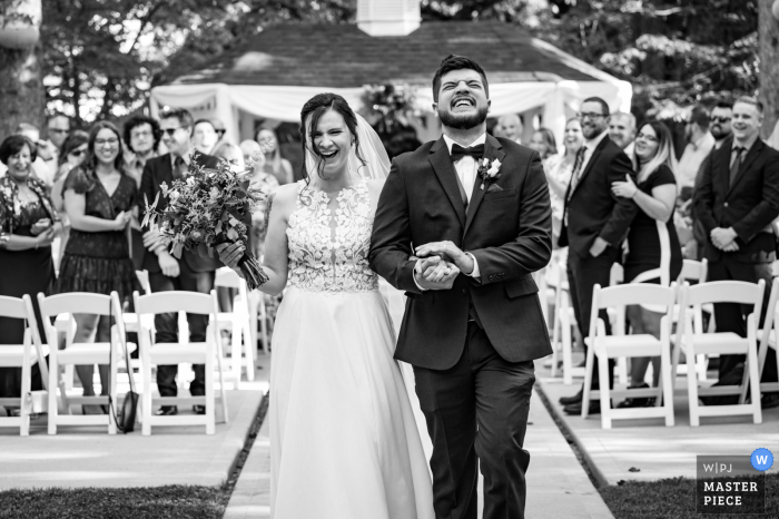 Colorado best wedding photography from Fort Collins showing a pic of A newly wed couple sharing a laugh as they exit their ceremony 