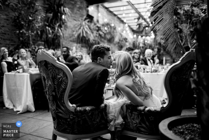 A top wedding photographer in Chicago, Illinois captured this picture showing the Couple has just sat down for dinner service and the guests started clinking their glasses