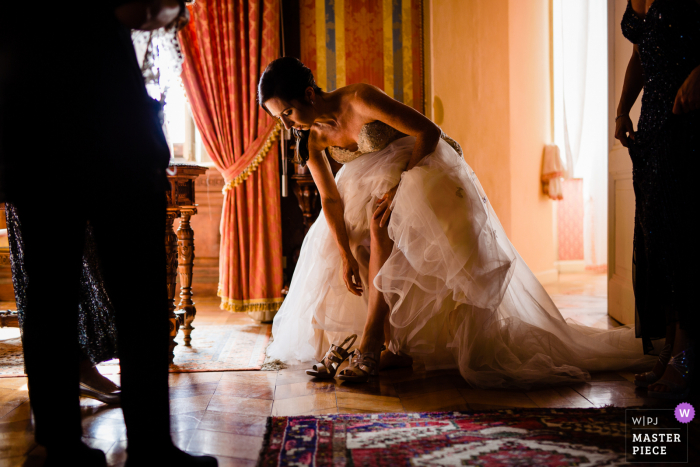 Best Italy wedding photography from Castello di Torre Alfina showing a pic of The bride  putting on her shoes 