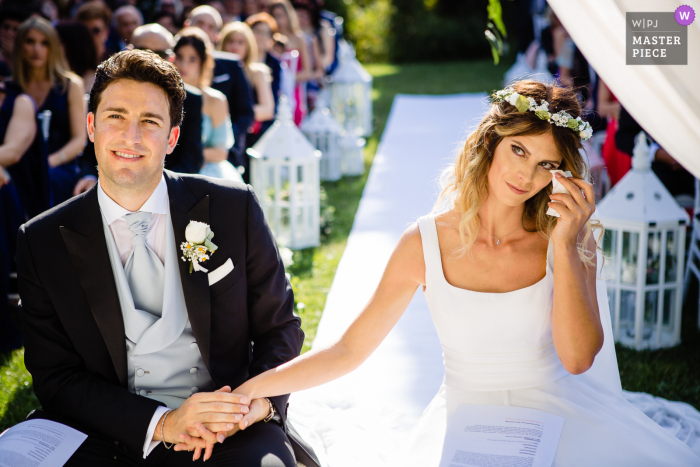 The bride couldn't hold her tears during the ceremony when her sister had their speeches A top Rome wedding photographer at Villa Pocci captured this picture showing The bride couldn't hold her tears during the ceremony when her sister had their speeches