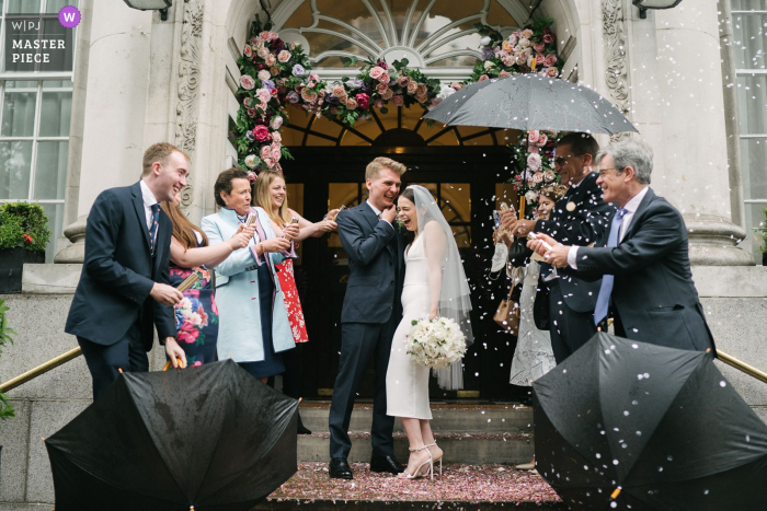 Czołowy fotograf ślubny w Wielkiej Brytanii w Chelsea Old Town Hall w Londynie uchwycił to zdjęcie konfetti rzuconego pannie młodej i panu młodemu na zewnątrz sali