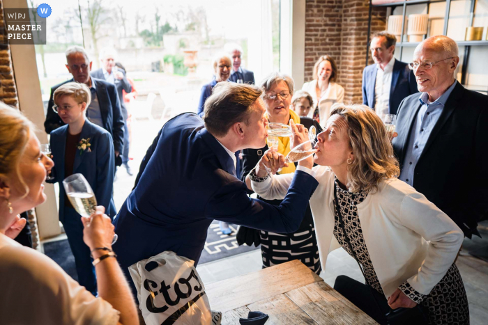 Melhor fotografia de casamento na Holanda de Buitenplaats Amerongen mostrando uma foto do noivo bebendo champanhe com um membro da família