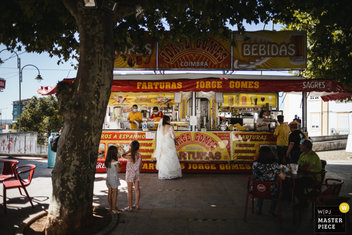 Um importante fotógrafo de casamentos de Portugal em Coimbra tirou esta foto da noiva em uma loja de comida de vendedor ambulante