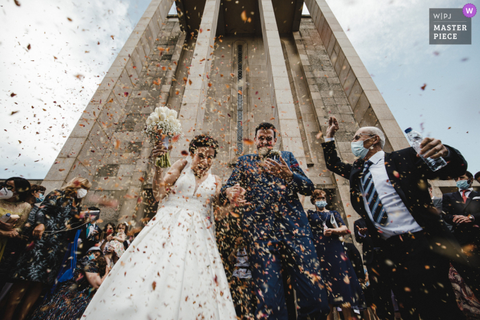 Beste Hochzeitsfotografie aus Porto, Portugal, die ein Bild einer Konfettidusche für das Brautpaar zeigt, das die Kirche verlässt