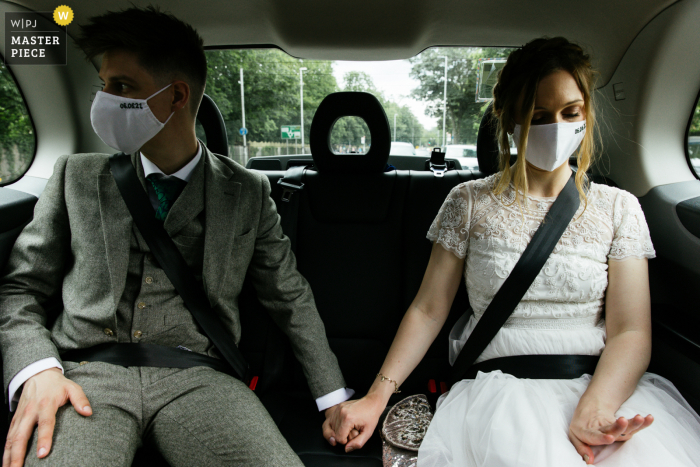 Best wedding photography from France showing a pic of The couple wearing facemasks whilst the bride looks at her new wedding ring 