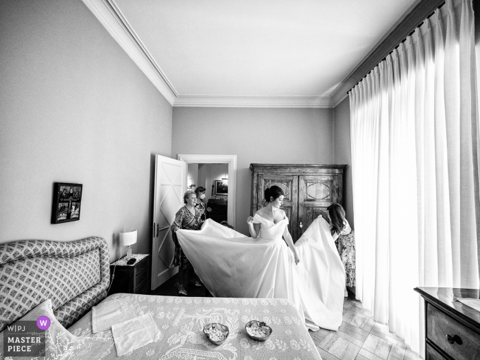 Fotografia di matrimonio a Milano di 4 donne e un abito da sposa, nessuna di loro riesce a togliere le pieghe dalla gonna