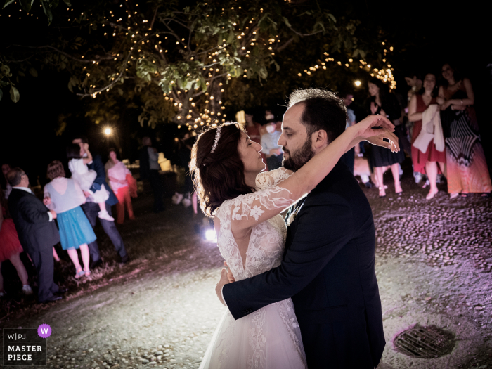 Italië beste huwelijksfotografie van het Castello di Cernusco in Lombardone met een foto van de bruid en bruidegom die dansen terwijl op de achtergrond alle gasten hen opgewonden bekijken