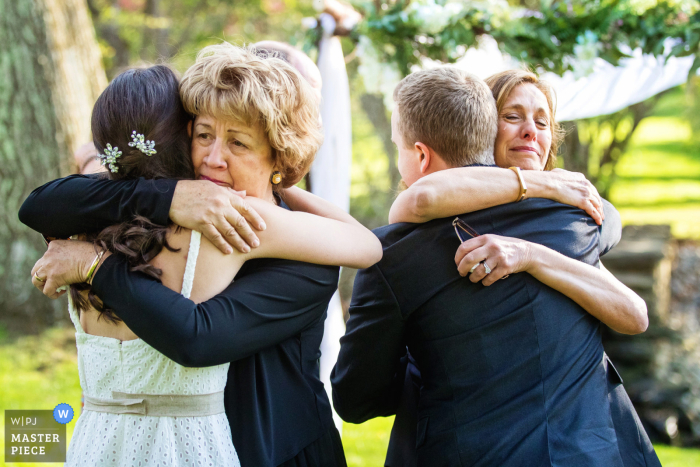 Ein Hochzeitsfotograf im Appleford Estate in PA hat dieses Bild einer Mutter geschaffen, die ihre Kinder nach einer intimen Zeremonie im Freien umarmt