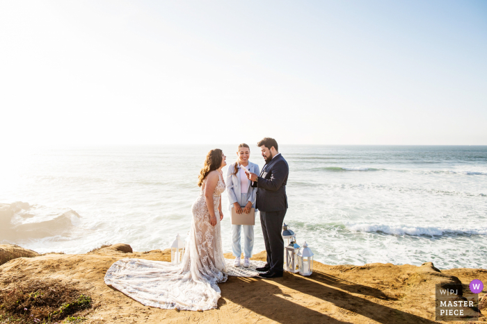 Een top huwelijksfotograaf bij Sunset Cliffs in San Diego maakte deze foto waarop de bruid lacht tijdens de geloften tijdens een intieme strandceremonie