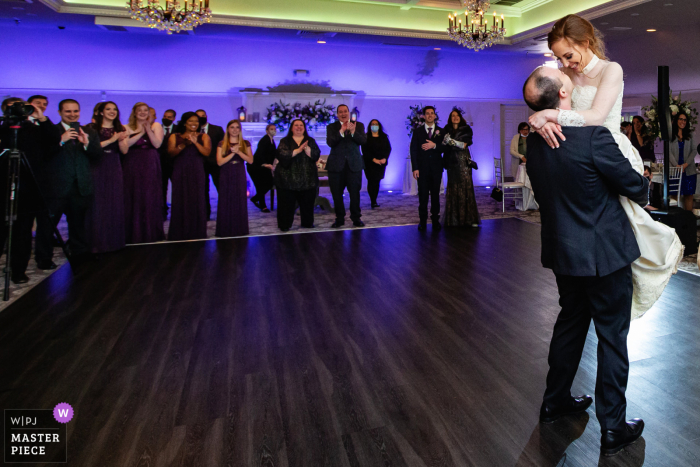 Beste Hochzeitsfotografie von Castle at Skylands Manor in New Jersey, die ein Bild des Bräutigams zeigt, der die Braut beim ersten Tanz im Schloss hochhebt