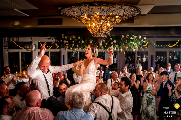 Best wedding photography from Virginia at the Stone Tower Winery showing A couple is lifted in the air during the Hora dance   