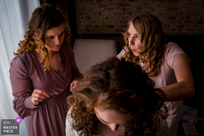 Um fotógrafo de casamento renomado no Appleford Estate em Villanova, PA tirou esta foto mostrando as damas de honra ajudando a noiva a se vestir