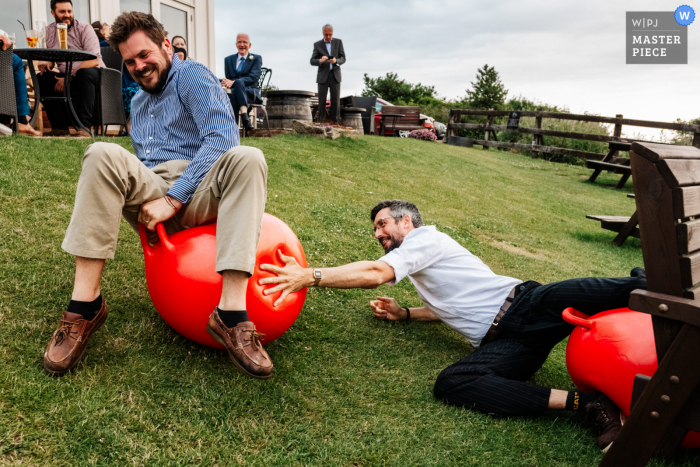  Robin Hoods Bay, Yorkshire, England wedding photography showing Two guests race space hoppers, as one falls off  