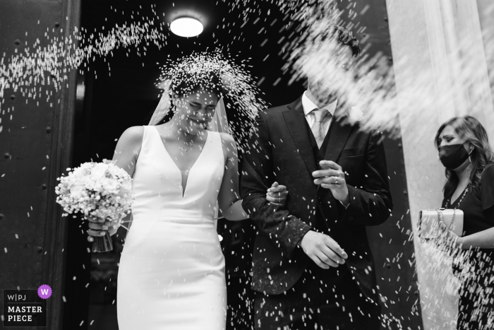 Iglesia de Génova, Italia, imagen ganadora del premio del día nupcial de la novia y el novio arrojándoles arroz después de la ceremonia. Los mejores concursos de fotografía de bodas del mundo son organizados por la WPJA