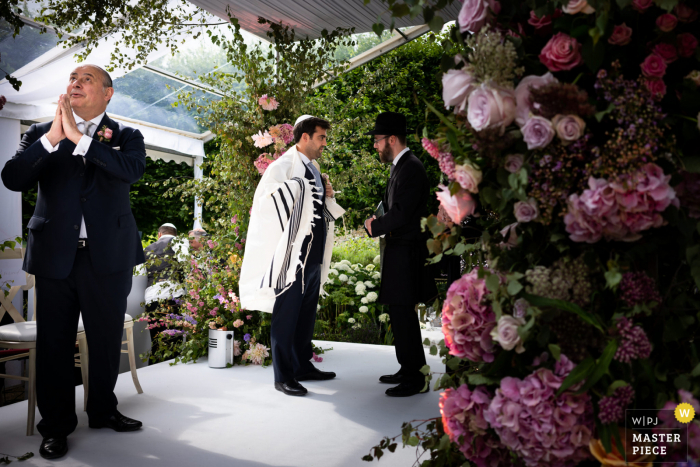 Gutting Manor, la imagen ganadora de premios de la ceremonia de matrimonio al aire libre de los Cotswolds que muestra al padre del novio dando las gracias por el clima. Los mejores concursos de fotografía de bodas del mundo presentados por la WPJA