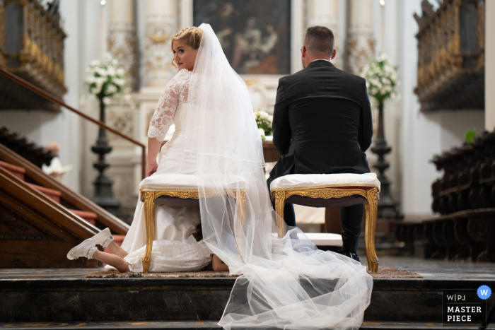 Siracusa Indoor-Hochzeitszeremonie preisgekröntes Bild, das einen wirklich lustigen Moment am Kirchenaltar zeigt. Die weltbesten Hochzeitsbildwettbewerbe werden über die WPJA vorgestellt