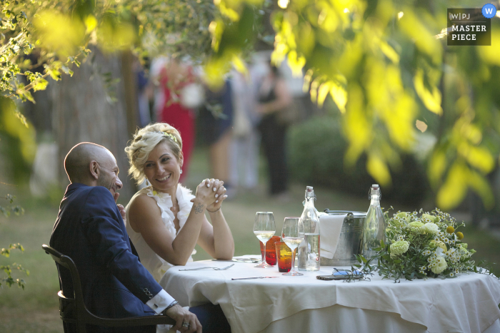 Ravenna Outdoor-Hochzeitsempfangsparty preisgekröntes Foto, das die Braut und den Bräutigam während des Empfangs am Tisch aufgenommen hat. Die besten Hochzeitsfotografen der Welt messen sich bei der WPJA